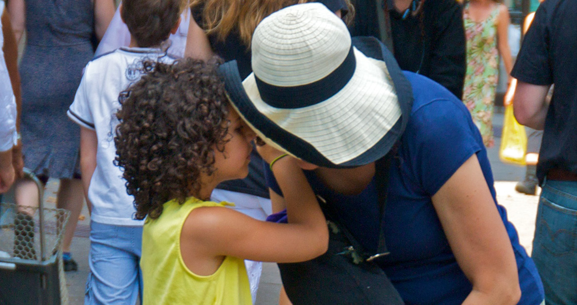 Girl whispering into woman's ear