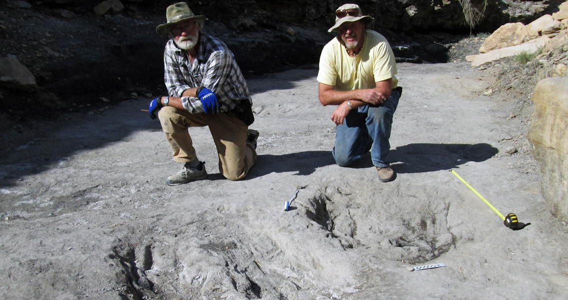 University of Colorado Denver researcher Martin Lockley (right) and Ken Cart pose beside large a dinosaur scrape they discovered in Western Colorado